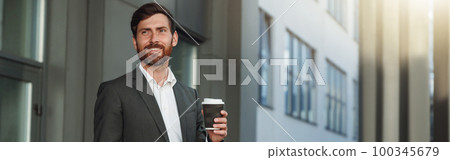 Confident european businessman in suit with laptop and coffee near office building Confident european businessman in suit with laptop and coffee near office building 100345679