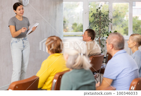 Young female teacher explaining subject to mature students 100346033