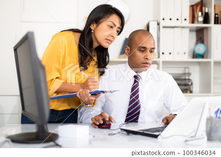 Businessman and female colleague working with papers and laptop 100346034