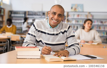 Cheerful adult hispanic student studying in university library Cheerful adult hispanic student studying in university library 100346138
