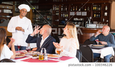 Delighted guests praising hispanic chef in pizza restaurant 100346226