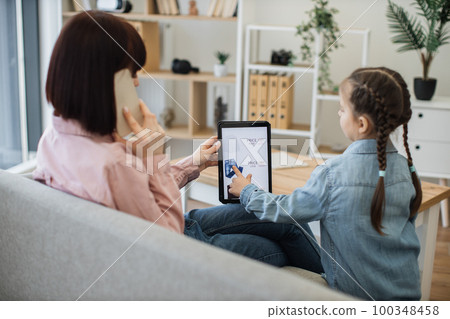 Woman with phone and tablet and girl ordering clothes online 100348458