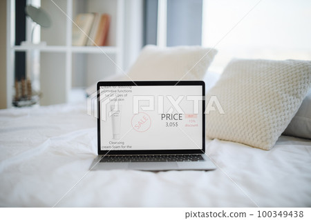 Laptop placed on bed with cosmetic website on screen 100349438
