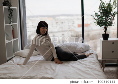 Caucasian woman resting at bedroom with panoramic windows 100349443