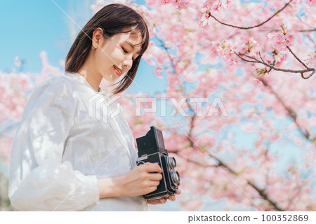 Young woman taking pictures of cherry blossoms 100352869