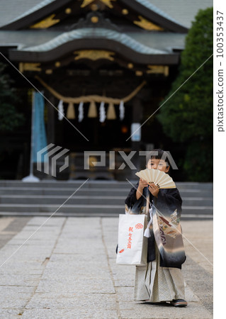 前來參拜七鄉神社的穿著和服的5歲小孩，以神社建築為背景，用扇子捂著嘴巴看著我們。 100353437