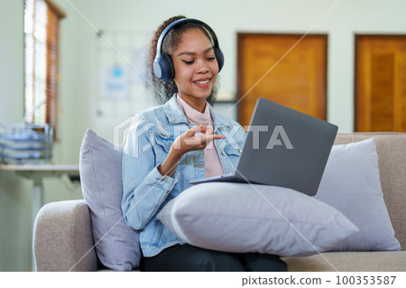 Portrait of an African American with headphones and a computer conferencing for a meeting over the Internet while working at home. 100353587