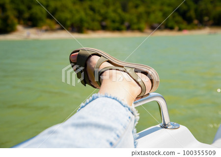 female leg in sandal, blue jeans on water pedal boat tourist catamaran on mountain lake on sunny day. summer leisure activities in public park. 100355509