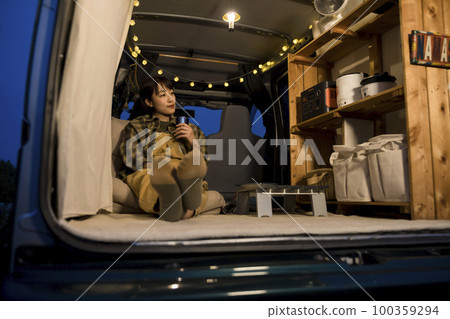 A young woman relaxing in her car at an auto-camping site at night Image of sleeping in a car A young woman relaxing in her car at an auto-camping site at night Image of sleeping in a car 100359294