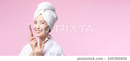 Portrait happy young asian woman with natural make up face holding cosmetic skin powder blusher isolated on pink background. Female apply skincare brush treatment. beauty product, cosmetology concept. Portrait happy young asian woman with natural make up face holding cosmetic skin powder blusher isolated on pink background. Female apply skincare brush treatment. beauty product, cosmetology concept. 100360808