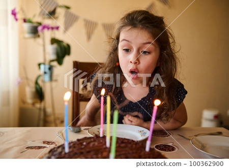 Lovely little child, cute baby girl with beautiful long curly hair, wearing elegant dress, blowing out candles on her birthday cake Lovely little child, cute baby girl with beautiful long curly hair, wearing elegant dress, blowing out candles on her birthday cake 100362900