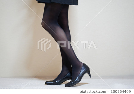 Legs wearing black stockings and black pumps sideways Legs wearing black stockings and black pumps sideways 100364409