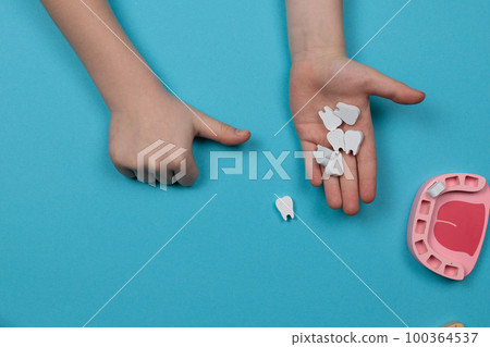 Children's hands hold toy teeth. Pediatric dentistry and dental treatment. Top view on blue background Children's hands hold toy teeth. Pediatric dentistry and dental treatment. Top view on blue background 100364537