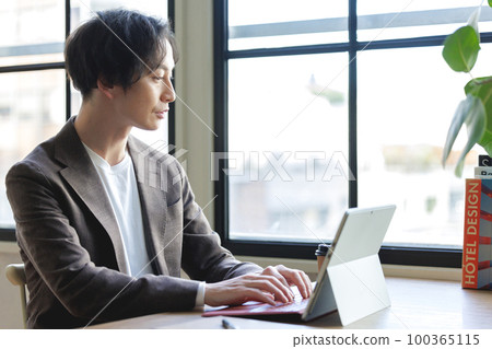 A man working on a computer by the window A man working on a computer by the window 100365115