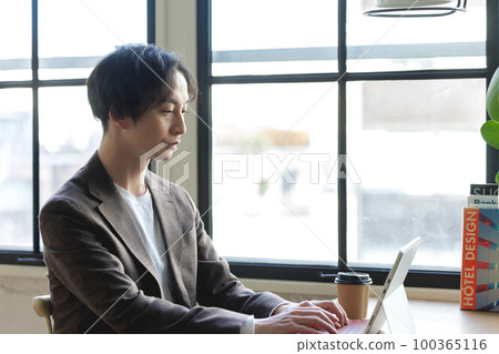A man working on a computer by the window A man working on a computer by the window 100365116