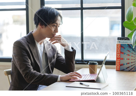 A man working on a computer by the window A man working on a computer by the window 100365118