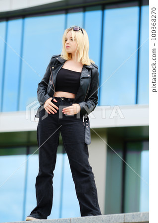 Young teenager girl in black top, jeans and leather jacket 100368270