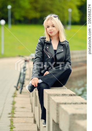 Portrait of funny teenager in total black outfit on river embankment 100368274