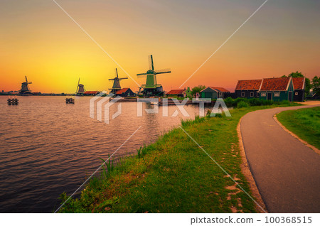 Sunset above farm houses and windmills of Zaanse Schans in the Netherlands 100368515