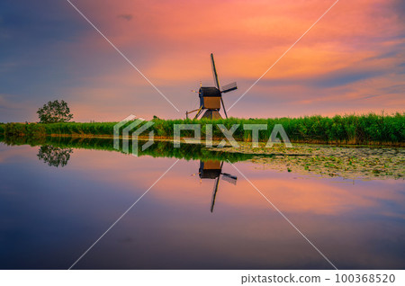 Sunset over an old dutch windmill by a river in Kinderdijk, Netherlands 100368520