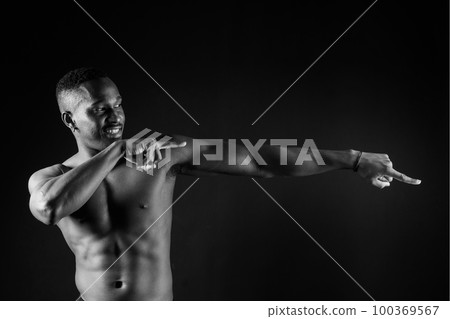 Athletic african american man topless, big muscles, dark background studio Athletic african american man topless, big muscles, dark background studio 100369567