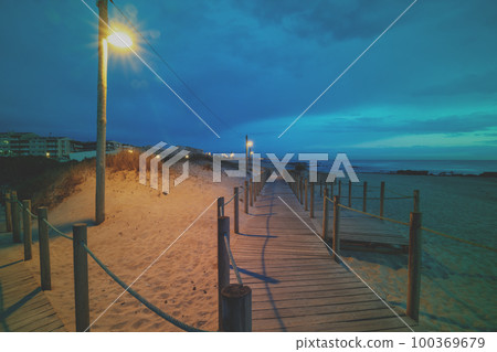 Wooden terrace on the sandy seashore after sunset. Beautiful beach in the evening. Coast of the Atlantic Ocean near Porto, Portugal 100369679