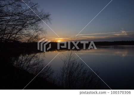 Dramatic sunset over a forest lake Dramatic sunset over a forest lake 100370306