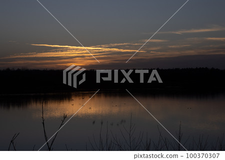 Dramatic sunset over a forest lake Dramatic sunset over a forest lake 100370307