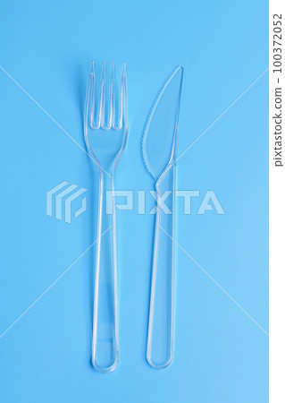 Plastic disposable tableware, cutlery. Fast food. Clean plastic fork and knive on blue background. Plastic disposable tableware, cutlery. Fast food. Clean plastic fork and knive on blue background. 100372052