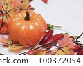 Pumpkin on a light background next to hot chili peppers and autumn maple leaves. 100372054