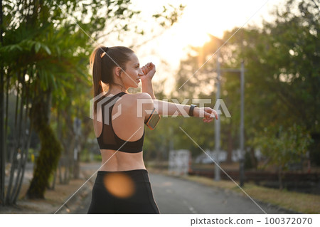 Sporty woman stretching her arms against nature view at sunny morning background. Fitness, sport and healthy lifestyle concept Sporty woman stretching her arms against nature view at sunny morning background. Fitness, sport and healthy lifestyle concept 100372070
