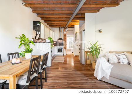 Luxury design of the living room. Kitchen of the studio with wooden beams parquet, modern furniture table and chairs. Overlooking the entrance to the bedroom with glass bricks Luxury design of the living room. Kitchen of the studio with wooden beams parquet, modern furniture table and chairs. Overlooking the entrance to the bedroom with glass bricks 100372707