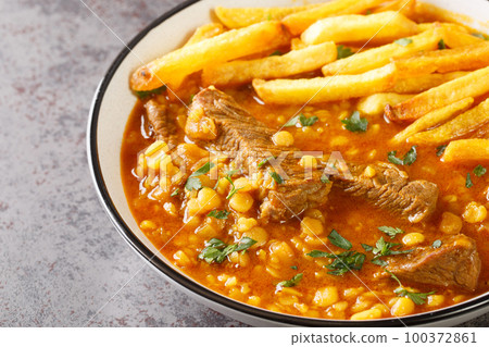 Gheimeh or Qeimeh is an Iranian stew consisting of diced mutton or beef, tomatoes, split peas, onion and dried lime, garnished with golden crispy potatoes closeup on a plate. Horizontal 100372861