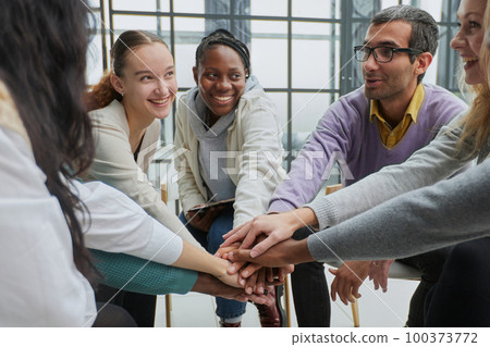 Diverse people sitting in circle holding hands at group therapy Diverse people sitting in circle holding hands at group therapy 100373772