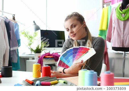 Female fashion designer seamstress working in studio holding color palette Female fashion designer seamstress working in studio holding color palette 100373809