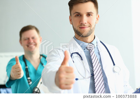 Two doctors gesture thumbs up in clinic recommending medical services Two doctors gesture thumbs up in clinic recommending medical services 100373888