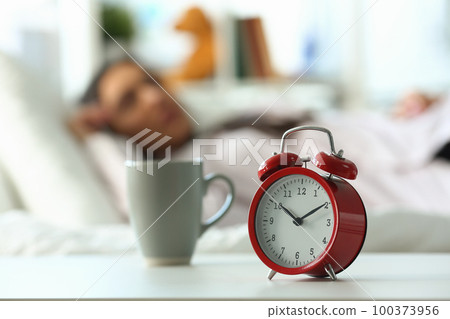 Red alarm clock at ten o'clock and sleeping woman Red alarm clock at ten o'clock and sleeping woman 100373956