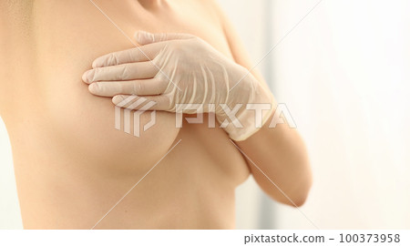 Naked woman examines breasts in gloved hands Naked woman examines breasts in gloved hands 100373958