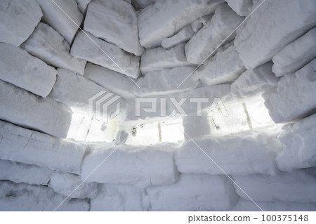 Inside view of wall of snow bricks and window made of ice in igloo, shelter from cold 100375148