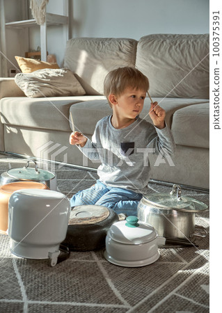 Child drummer having fun drum playing on kitchen pans at home Child drummer having fun drum playing on kitchen pans at home 100375391