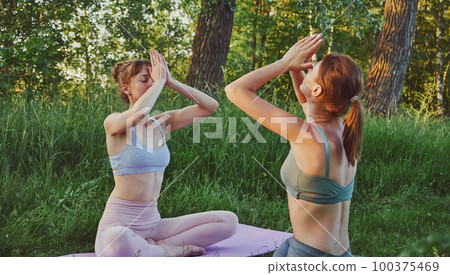 Two young women doing yoga anjali mudra outdoors, mental health care Two young women doing yoga anjali mudra outdoors, mental health care 100375469
