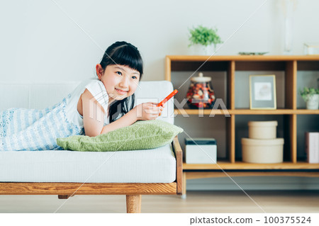 Elementary school girl looking at smartphone in living room Elementary school girl looking at smartphone in living room 100375524