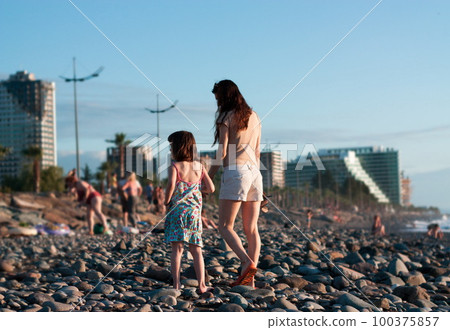 Mother with child girl at the sea beach on sunset 100375857