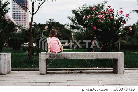 Little girl sitting alone on the bench 100376450