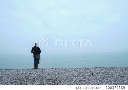 Woman looking out over a foggy sea Woman looking out over a foggy sea 100379589