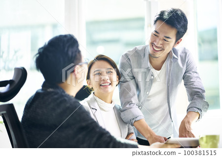 three young asian teammates working together having a pleasant business discussion in office 100381515
