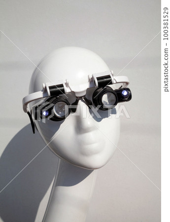 Mannequin wearing double eye magnifying glasses with LED light illumination. High magnification lens handsfree glasses for professionals, specialists, scientists, jewelers Mannequin wearing double eye magnifying glasses with LED light illumination. High magnification lens handsfree glasses for professionals, specialists, scientists, jewelers 100381529