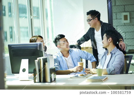 four young asian business people conversing in office, happy and relaxed 100381759