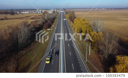 Cars driving along the highway on an autumn sunny day. Automobile road with white markings between agricultural fields. View of the cars driving on paved road. automobile vehicles. Aerial drone view. 100383479