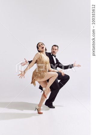 Excited man and adorable woman in vintage evening festive outfits dancing retro ballroom dance with bright emotions. Concept of love and music, eras comparison Excited man and adorable woman in vintage evening festive outfits dancing retro ballroom dance with bright emotions. Concept of love and music, eras comparison 100383612